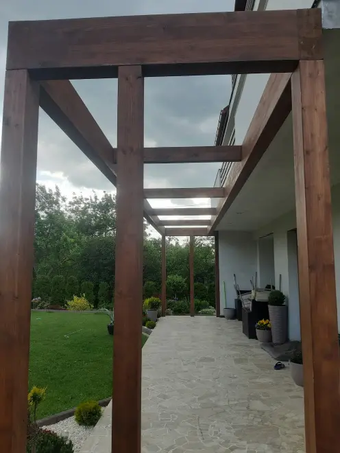 alt="Nowoczesna pergola z drewna klejonego z bezpiecznym zadaszeniem z szyby hartowanej"