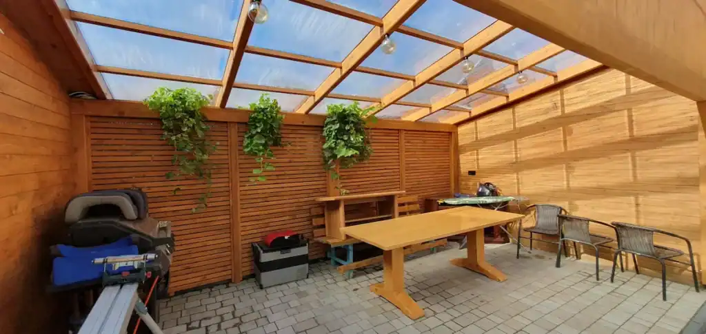 alt="Zabudowana pergola tarasowa z parawanem drewnianym i dachem z poliwęglanu – Rzeszów i okolice"