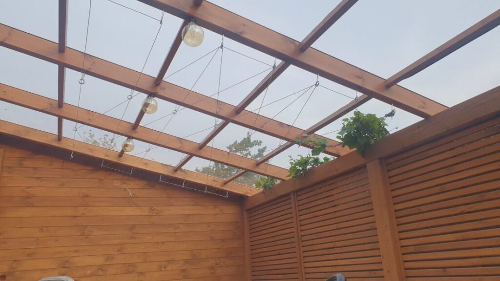 alt="drewniana pergola z dachem z poliwęglanu i stalowymi linkami na winogron – Rzeszów i okolice"